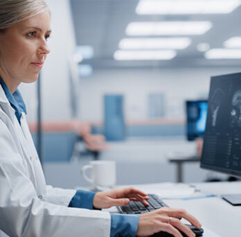 Healthcare administrator reviewing electronic health records on a desktop computer 